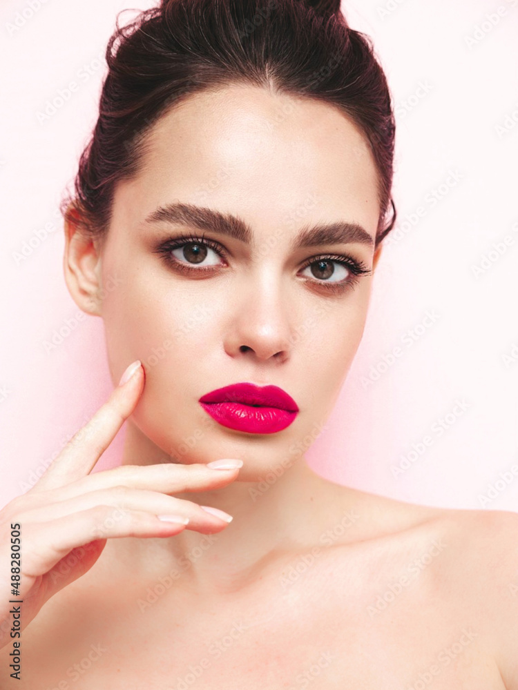 Fashion beauty portrait of young brunette woman with evening stylish makeup and perfect clean skin. Sexy model with hair in a bun posing in studio near white wall. With pink bright natural lips Fashion beauty portrait of young brunette woman with evening stylish makeup and perfect clean skin. Sexy model with hair in a bun posing in studio near white wall. With pink bright natural lips
