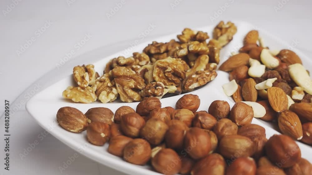 Various nuts close-up on a rotating white plate on a white wooden table. 4k raw video. Various nuts close-up on a rotating white plate on a white wooden table. 4k raw video.