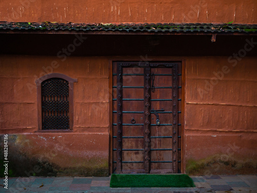 Wooden door and artistic window with red colored wall. photo