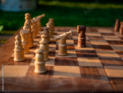 Wooden chess board with wooden pieces with sunlight.