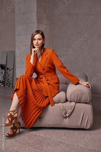 Fashion woman in trendy orange brown jacket and skirt.