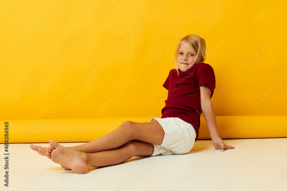 little girl sitting on the floor on a yellow background