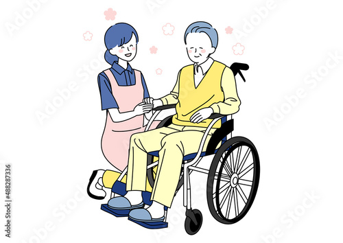 車椅子に乗るシニアと手を握る介護士