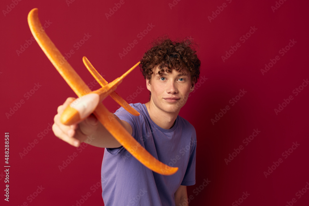 young guy with toy airplane entertainment red background unaltered