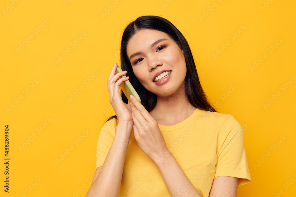 Charming young Asian woman communicates on the phone emotions studio model unaltered