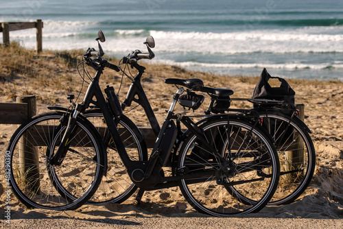 two electric bicycles posed next to the ocean beach in Nouvelle-Aquitaine photo