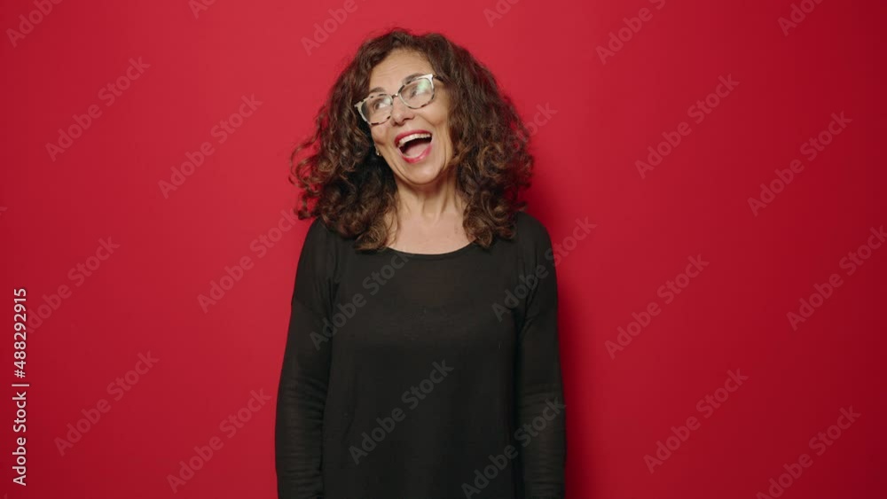 Middle age woman smiling confident standing over red background Middle age woman smiling confident standing over red background