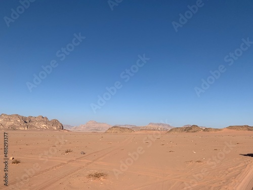 traces of cars in the sand against the background of stone cliffs in the desert  sand  rocks and blue sky