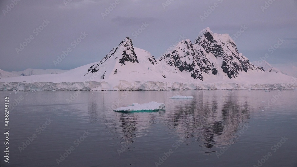 Icebergs and glaciers in Antarctica. Beautiful blue iceberg with mirror reflection floats in open ocean. Global Climate changes video - the glaciers are warming and melting faster.