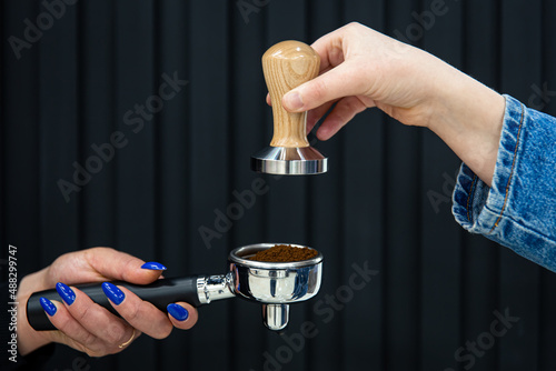 Female hands hold a holder with coffee and temperature on a black background. photo