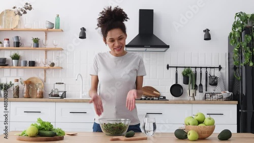 African American young female preparing salad in home kitchen. Beautiful woman using camera and video call cooking healthy food, breakfast or dinner for his followers. Healthy lifestyle concept