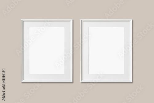 Picture frame mockup. Set of two vertical white frames on warm neutral wall background. Empty, blank template for artwork, painting or poster.