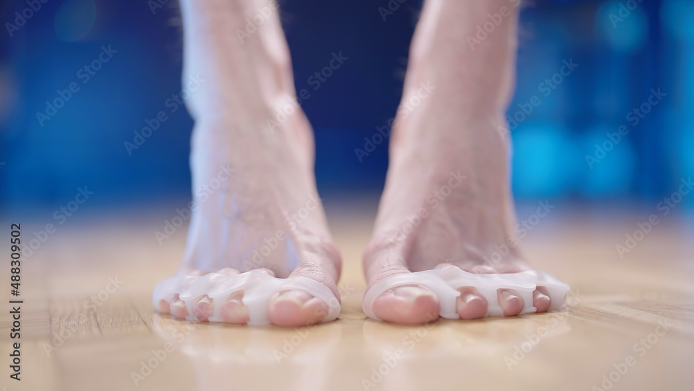 Person feet with silicone toe corrector spreader step on toes close-up Person feet with silicone toe corrector spreader step on toes close-up