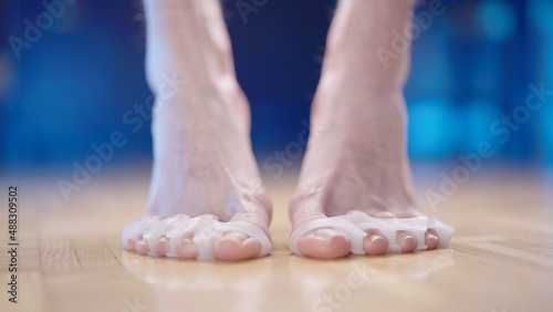 Person feet with silicone toe corrector spreader step on toes close-up