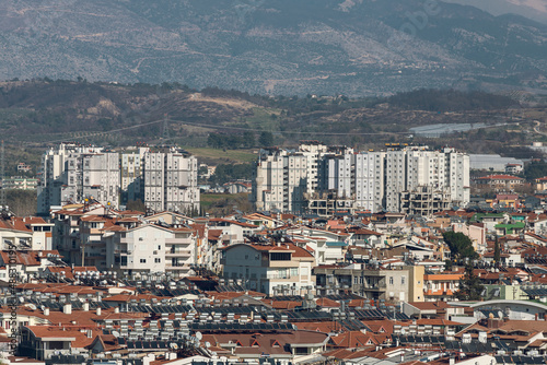 Residential area in a tropical country with many similar houses with water barrels basking in the sun, mountain at the background , soft focus