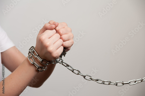 Teenager's hands are tied with a metal chain. The social problem of juvenile delinquency photo