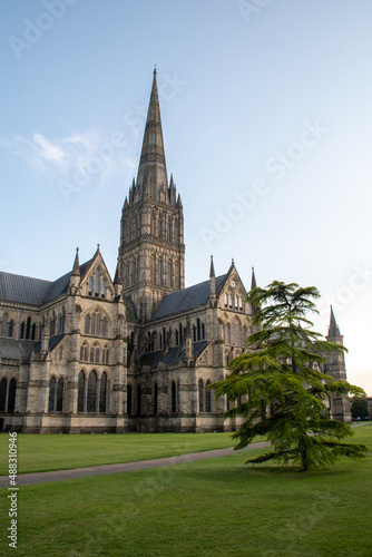 The spire of Salisbury Cathedral, Wiltshire, against a clear blue sky at golden hour. July 2021