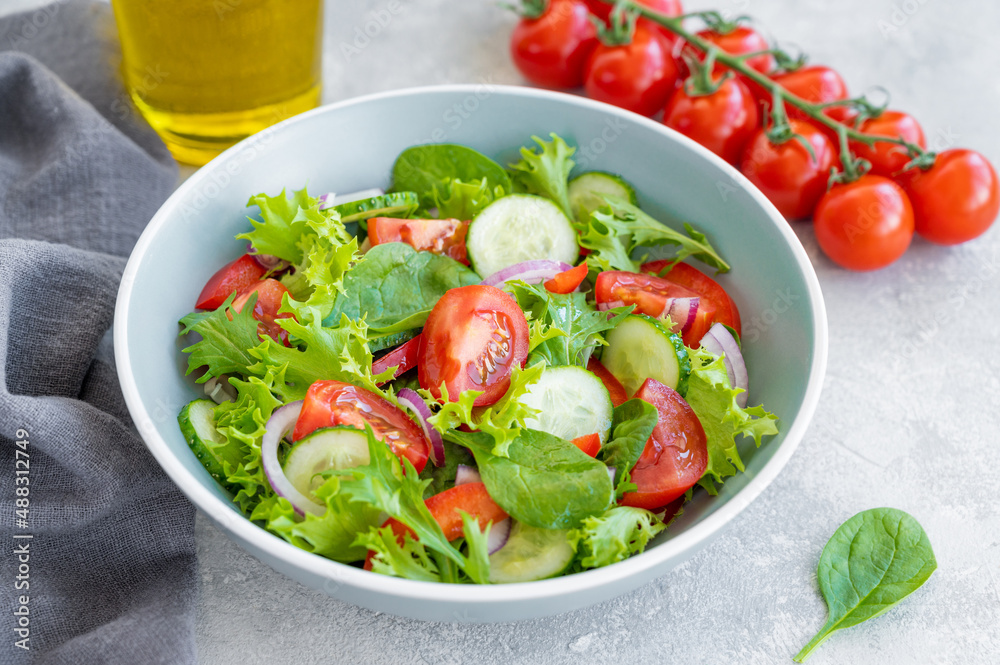 Salad with fresh vegetables and cheese in a bowl on a concrete background. Greek salad, vegetarian dish. Top view.