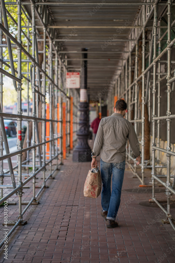 Man holding a bag under scaffolding Man holding a bag under scaffolding