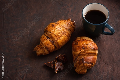 delicious, crispy croissants, chocolate, hot coffee in the blue cup on plate on dark table. Tasty breakfaste. French pastries. Top view. Breakfast aristocrat. Tasty eat photo