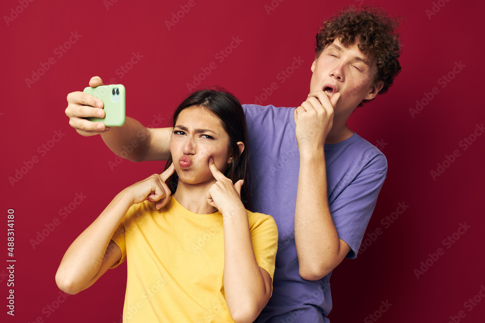 nice guy and girl in colorful T-shirts with a phone red background nice guy and girl in colorful T-shirts with a phone red background