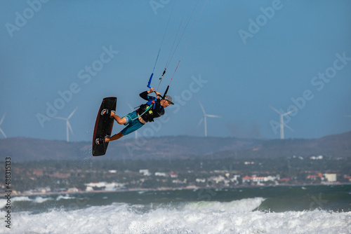 Vietnamese kitesurfer jumping with a kiteboard in the transition against the backdrop of windmills