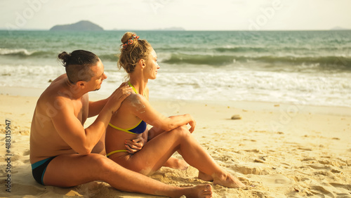 Hot sexy loving couple having sun block. Woman to put sunscreen man. Young girl and guy in hugging using sun cream. Concept rest tropical resort, traveling tourism happy summer holidays