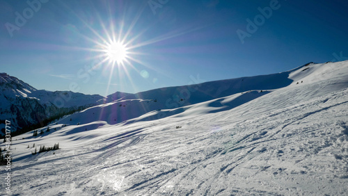 Sun over a snowy alpine ski slope  © Petr