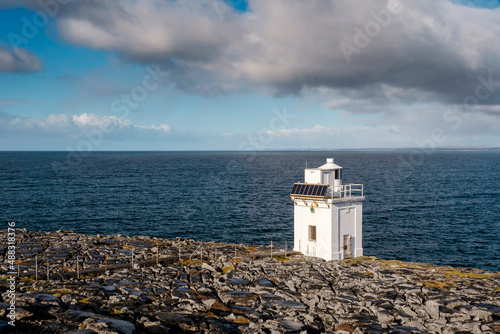 Black Head Lighthouse in Burren, Ireland. Galway bay in the background. Blue cloudy sky. Famous landmark on Wild Atlantic Way tourist route.