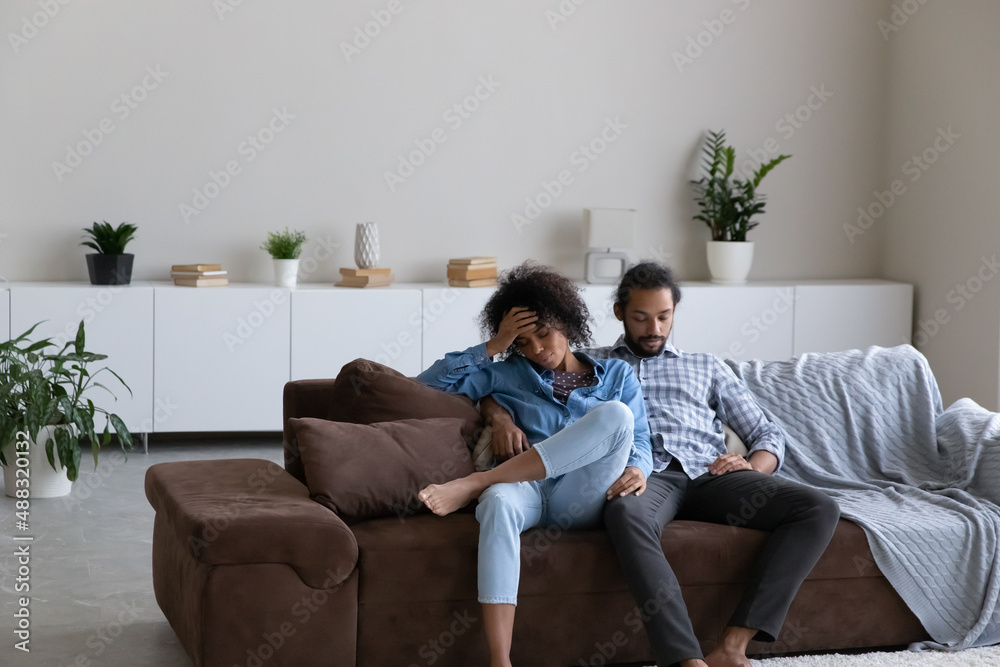 Frustrated young African American couple feeling tired after had working day, resting together on comfortable sofa at home. Unhappy stressed exhausted multiracial man and woman sleeping indoors. Frustrated young African American couple feeling tired after had working day, resting together on comfortable sofa at home. Unhappy stressed exhausted multiracial man and woman sleeping indoors.
