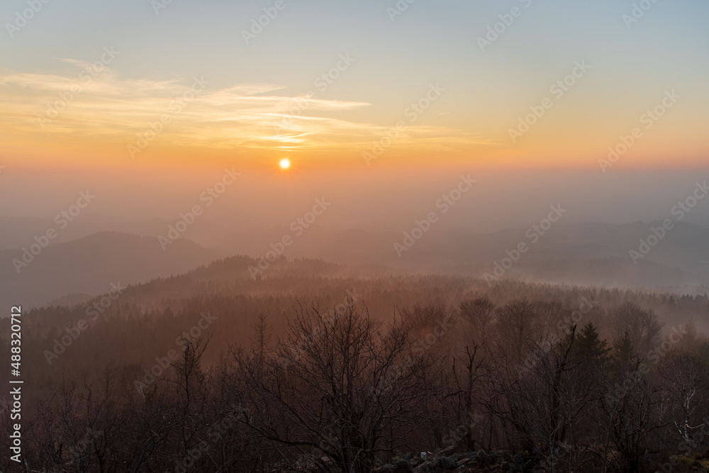 peaks of lusatian mountains in Czech Republic during foggy sunset in winter as seen from mount Hochwald in Germany