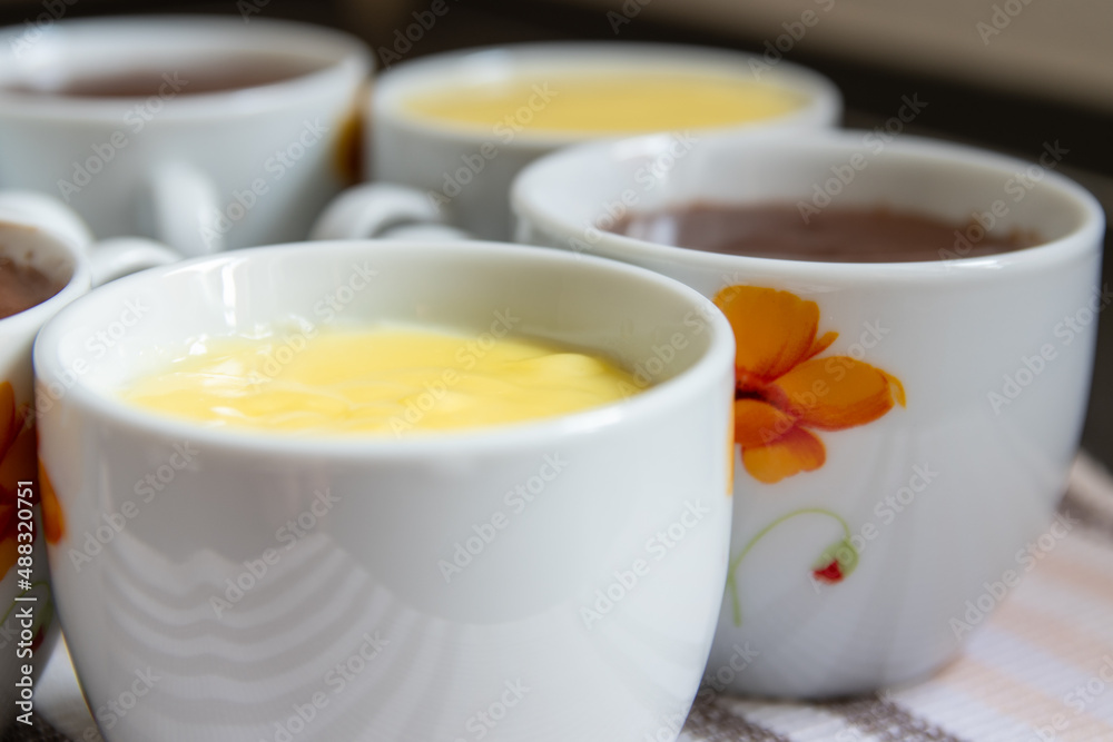 close-up shot of porcelain cups filled with yellow vanilla and brown chocolate flummery close-up shot of porcelain cups filled with yellow vanilla and brown chocolate flummery