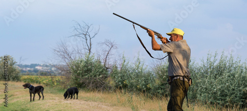 Hunter man in camouflage with a gun during the hunt in search of wild birds or game. Autumn hunting season.