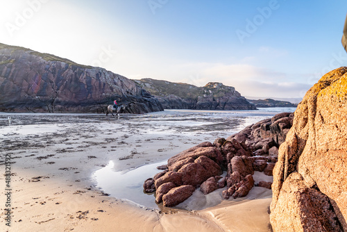 Horse riding at Cloughglass bay and beach by Burtonport in County Donegal - Ireland photo