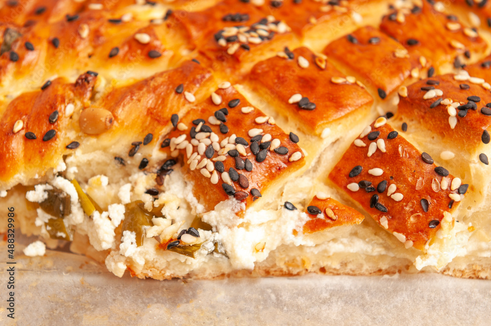 salty pie of puff pastry sprinkled with sesame on a wooden background salty pie of puff pastry sprinkled with sesame on a wooden background