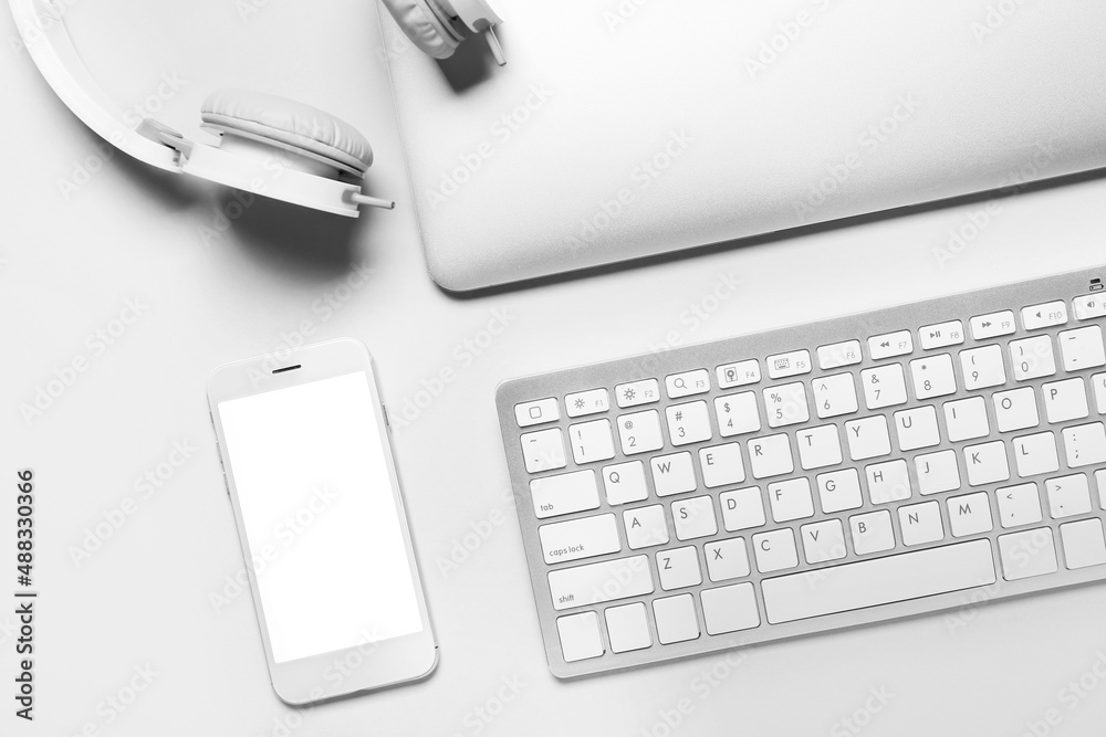 Mobile phone, keyboard, laptop and headphones on white background, closeup Mobile phone, keyboard, laptop and headphones on white background, closeup
