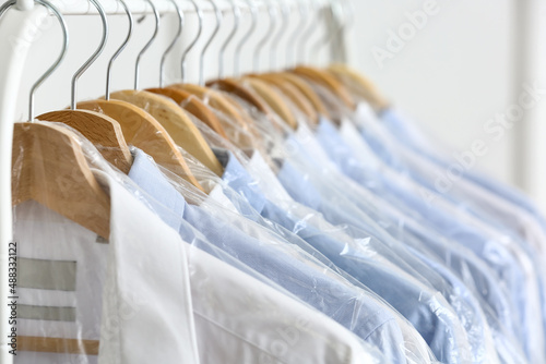Fotografering Rack with clean shirts in plastic bags near light wall
