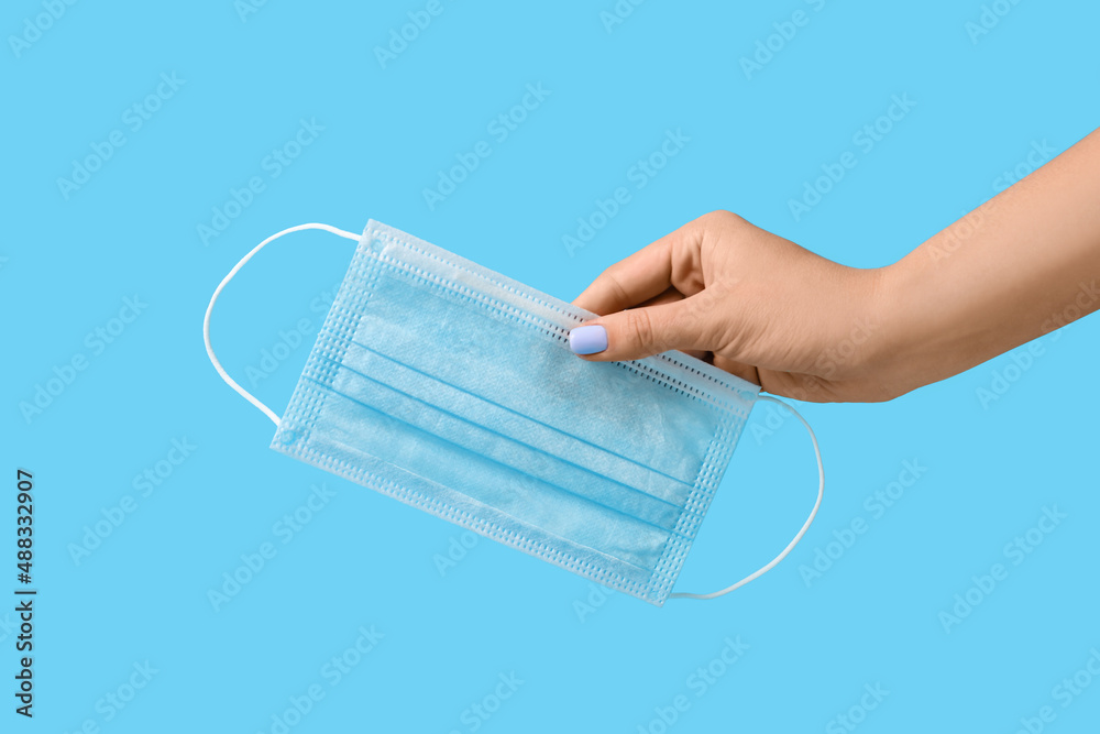 Female hand with medical mask on color background Female hand with medical mask on color background