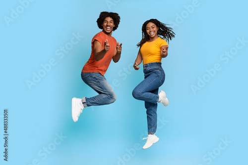 Happy african american lovers celebrating success on blue