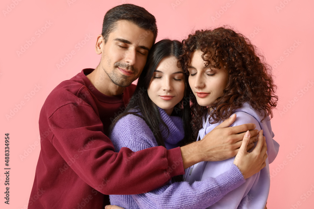 Man and two beautiful women on color background. Polyamory concept Man and two beautiful women on color background. Polyamory concept
