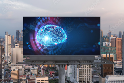 Brain hologram on billboard with Kuala Lumpur cityscape background at sunset. Street advertising poster. Front view. KL is the largest science hub in Malaysia, Asia. Coding and high-tech science.