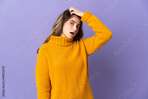 Young caucasian woman isolated on purple background doing surprise gesture while looking to the side © luismolinero