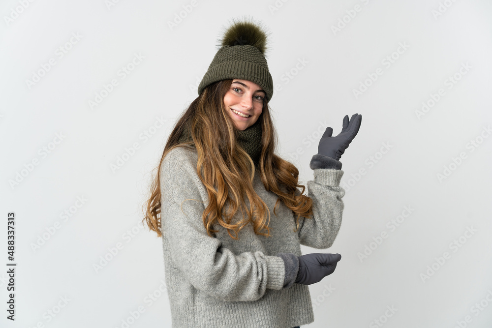 Young caucasian woman with winter hat isolated on white background extending hands to the side for inviting to come Young caucasian woman with winter hat isolated on white background extending hands to the side for inviting to come