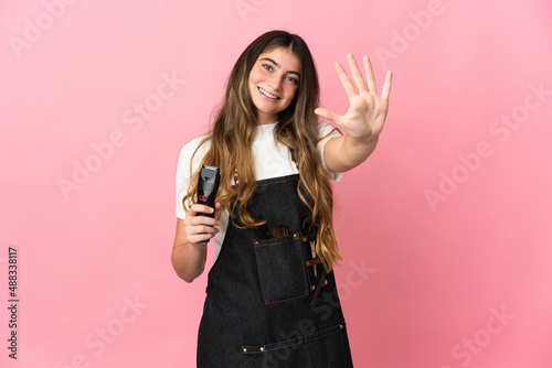 Young hairdresser woman isolated on pink background counting five with fingers