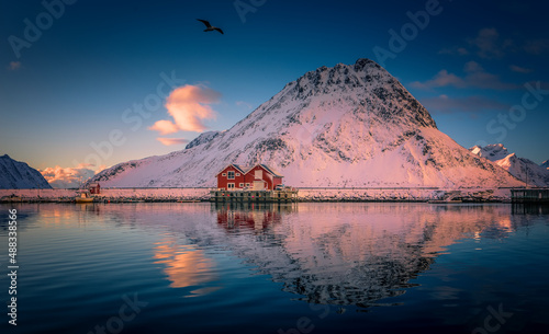 Lofoten islands. Norway. Wonderful nature of north. View on fjord, fishing huts and snowcovered mountais during sunset. Lofoten islands is a best travel and resting locations.