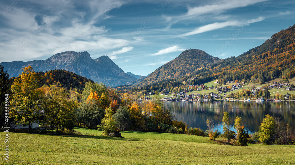 Scenic panorama of beautiful alpine autumn view with lake, mountains, green meadow and perfect sky. Amazing nature scenery. Wonderful sunny landscape. Grundlsee. Austria