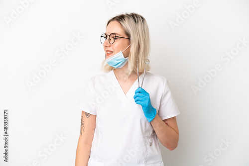 Dentist caucasian woman holding tools isolated on white background looking side