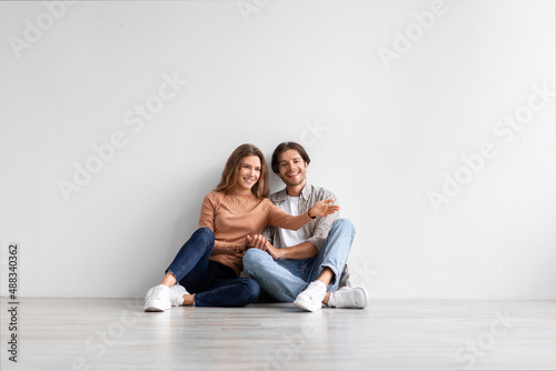 Smiling millennial caucasian man and lady celebrate buying own apartment, planning interior in empty room