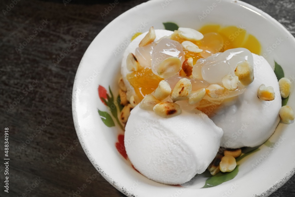 Thai style coconut ice cream topping with roasted peanuts, sweet pineapple and sweet palm kernels, serving on vintage enamelware Thai style coconut ice cream topping with roasted peanuts, sweet pineapple and sweet palm kernels, serving on vintage enamelware