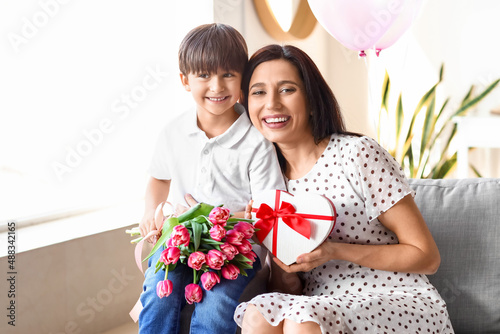 Little son and his mother with gift and bouquet of flowers for International Women's day at home